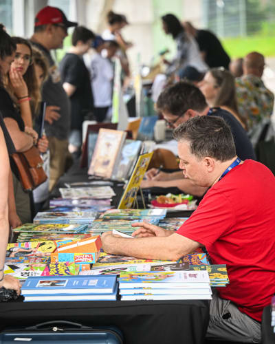 Festival de la BD de Prévost - Des bédéistes assis à des tables rencontrent des personnes