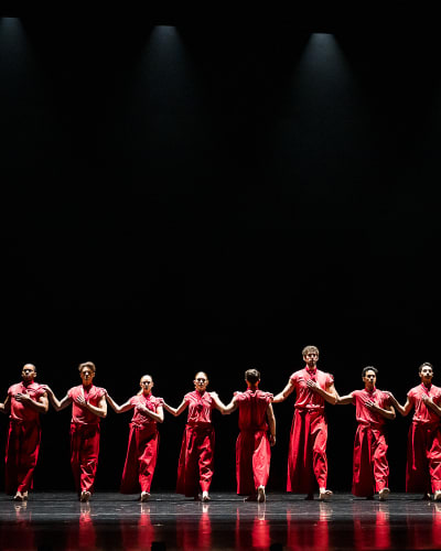 Festival des Arts de Saint-Sauveur - Dancers dressed in red are lined up on a dark stage.