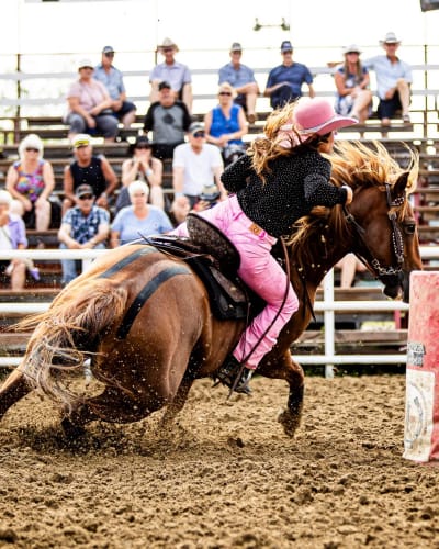 Woman participating in a barrel race at the Guigues Western Festival.
