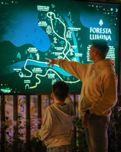 Foresta Lumina au Parc de la Gorge de Coaticook - A man and a boy point to an illuminated map.