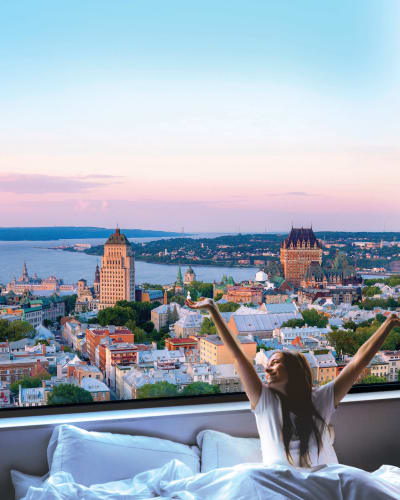 A woman waking up in a cozy bed with a spectacular view of Québec City.