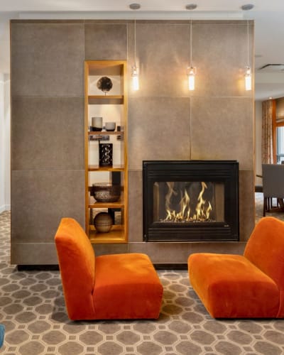 Hotel 2170 Lincoln - Deux chaises oranges devant un foyer allumé