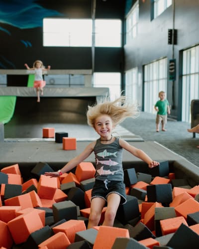 Une fille saute dans un bassin de blocs de mousse à iSaute.