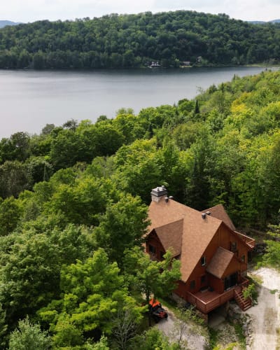 Vue aérienne d'un chalet près d'un lac en été.