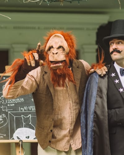 La Grande Échappée - A person dressed as a magician accompanied by a person dressed as a monkey.