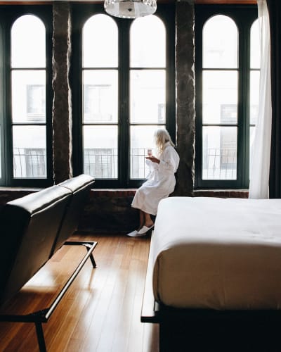 Le Petit Hôtel - Une personne en peignoir est assise sur le bord des fenêtres dans une chambre