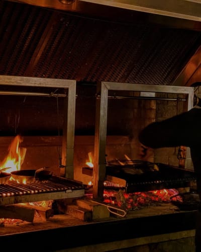 A cook preparing food over hot coals. 
