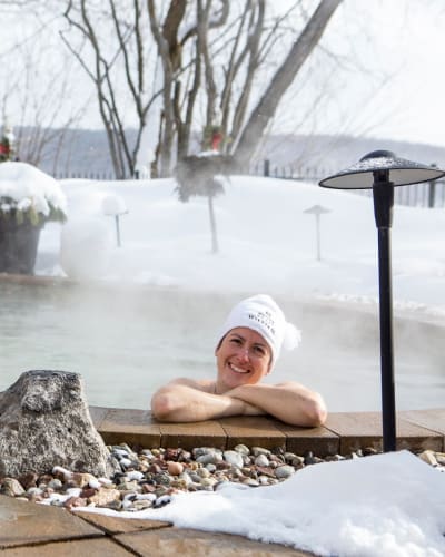 Woman in the outdoor spa at Manoir du Lac William in winter.
