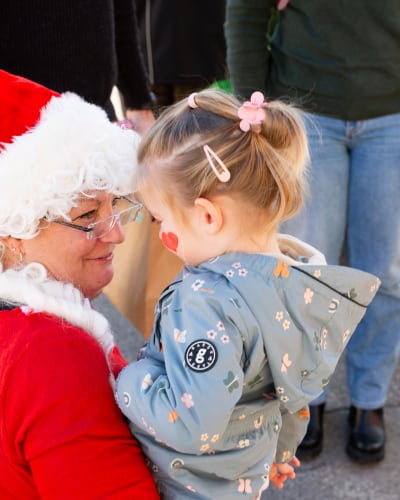 Prévost Christmas Market - A woman dressed as Mother Christmas is holding a child in her arms.
