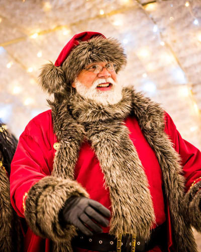 Santa Claus walking through an illuminated passage.