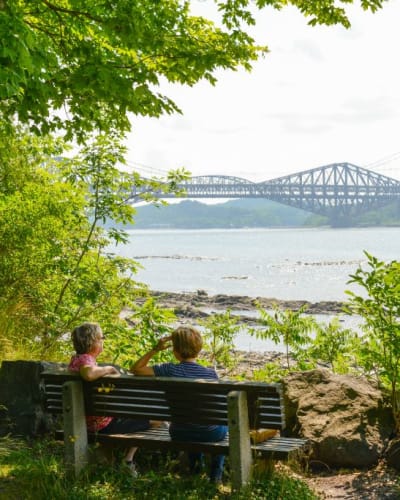 Deux personnes assises sur un banc l'été au Parc de la plage Jacques-Cartier.