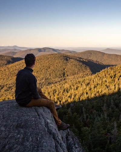 A hiker at the summit in autumn at Parc d'environnement naturel de Sutton.