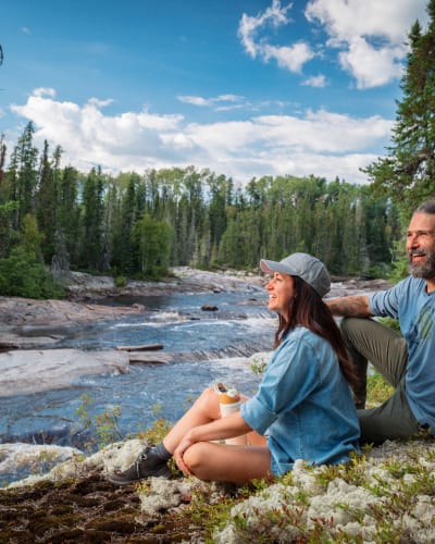 A man and a woman sitting by the river in the summer. 