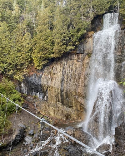 Floating bridge in front of waterfalls: Parcours Aventures - Via ferrata Gaspésie.