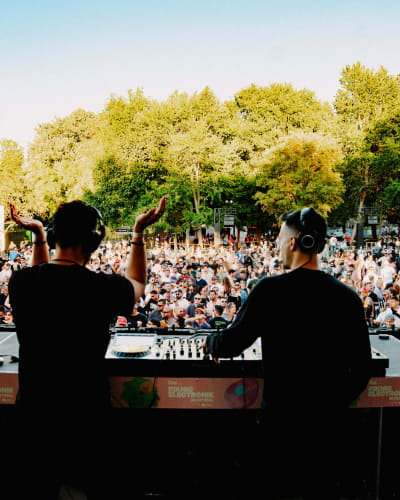 Two DJs on stage in front of the crowd.