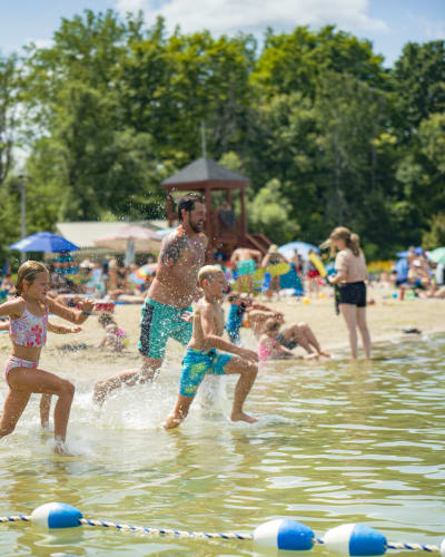 Famille courant dans l'eau à la plage.