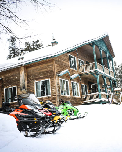 Snowmobiles next to the Pourvoirie Lac Dumoulin lodge.