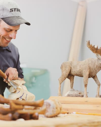Sculpteur et orignal en bois.