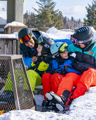 Family sitting at the foot of the mountain at Sommet Saint-Sauveur.