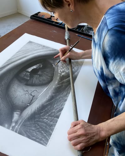 Tour des Arts - Une artiste travaille sur un dessin au fusain très détaillé d'un œil humain