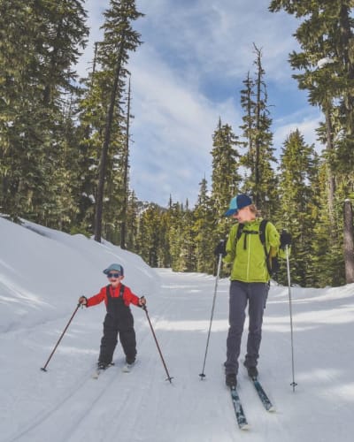 A mother and her young child doing cross-country skiing.