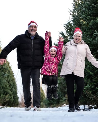 Une famille marche à côté de sapins au Village de Noël - Sapins Goupil.
