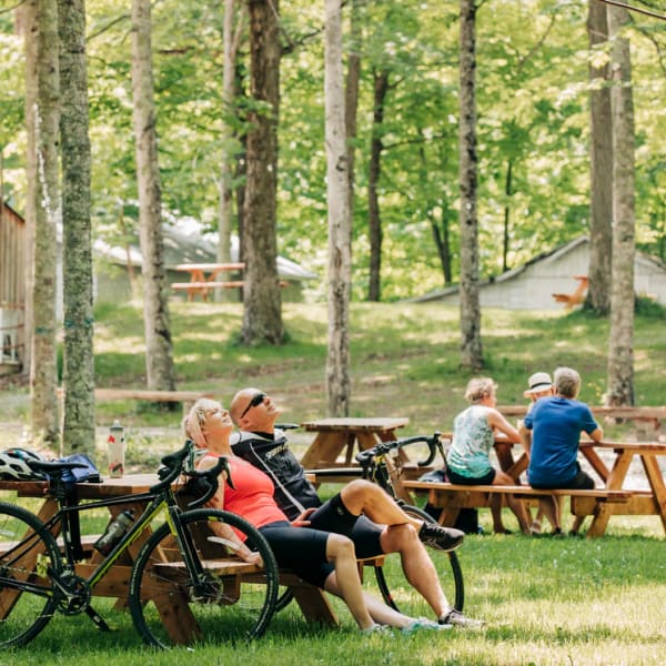 Érablière du Village -  Un homme et une femme sont assis à une table de pique-nique, avec leurs vélos appuyés sur celle-ci.