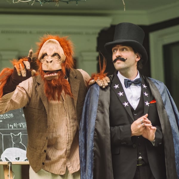 La Grande Échappée - A person dressed as a magician accompanied by a person dressed as a monkey.