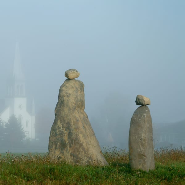 Les Amis du Patrimoine de Saint-Venant-de-Paquette - Deux sculptures en pierre, avec une église en arrière-plan