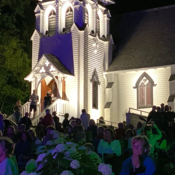 Chapelle du Lac - A crowd outside an illuminated white chapel at night