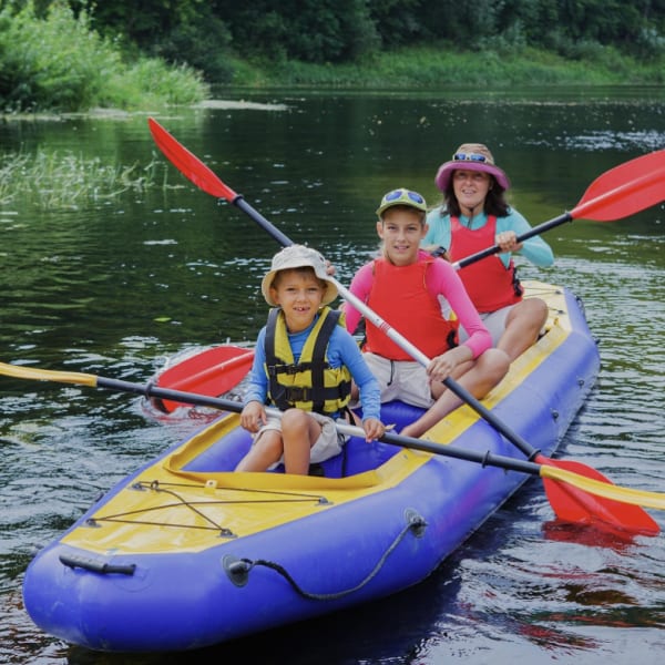 Family kayaking on an inflatable kayak on a river.