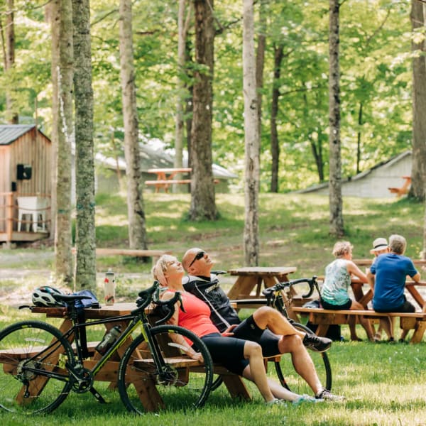 Érablière du Village -  Un homme et une femme sont assis à une table de pique-nique, avec leurs vélos appuyés sur celle-ci.