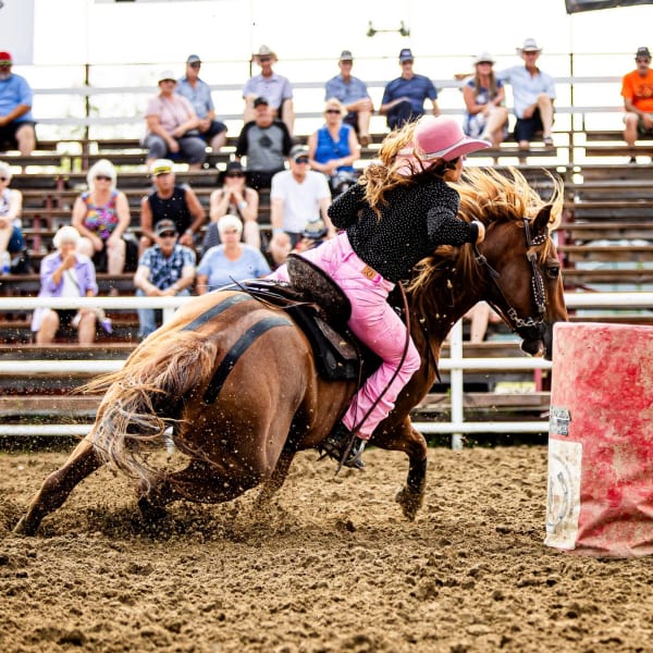 Woman participating in a barrel race at the Guigues Western Festival.
