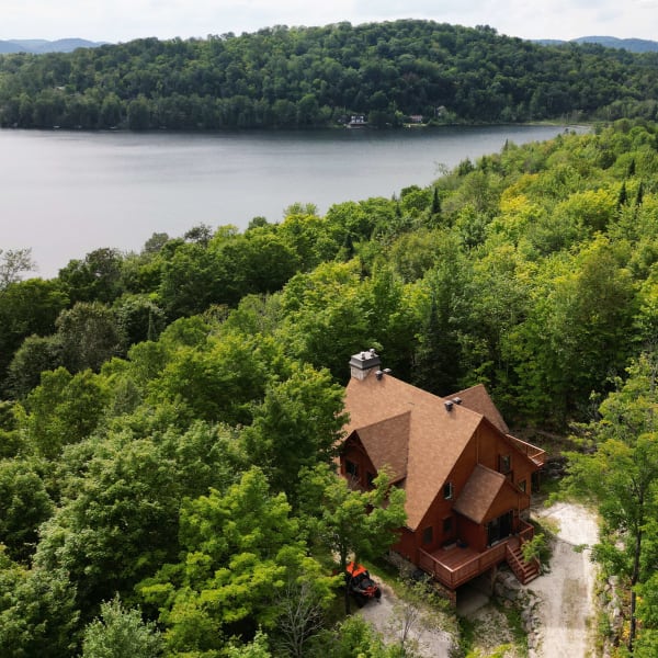 Aerial view of a cabin near a lake in summer.