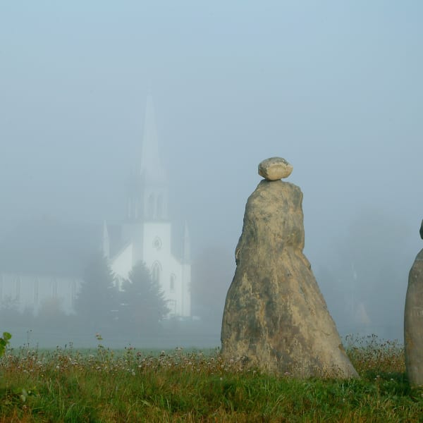 Les Amis du Patrimoine de Saint-Venant-de-Paquette - Deux sculptures en pierre, avec une église en arrière-plan