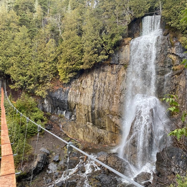 Floating bridge in front of waterfalls: Parcours Aventures - Via ferrata Gaspésie.