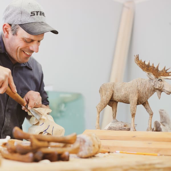 Sculpteur et orignal en bois.