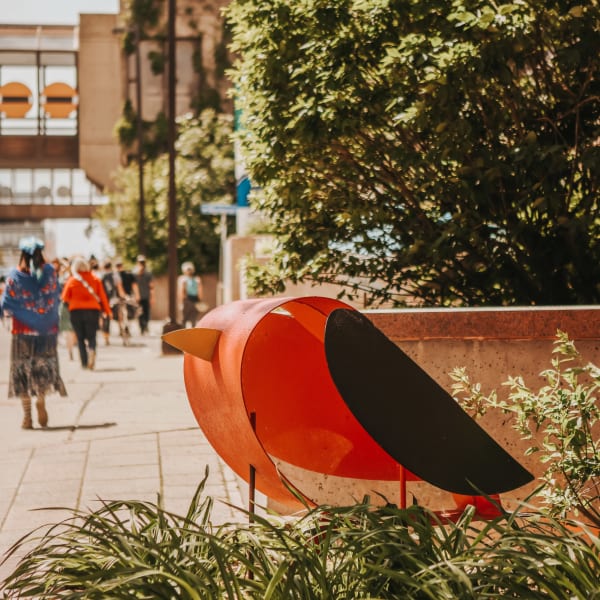 A sculpture of a bird on a sidewalk. 