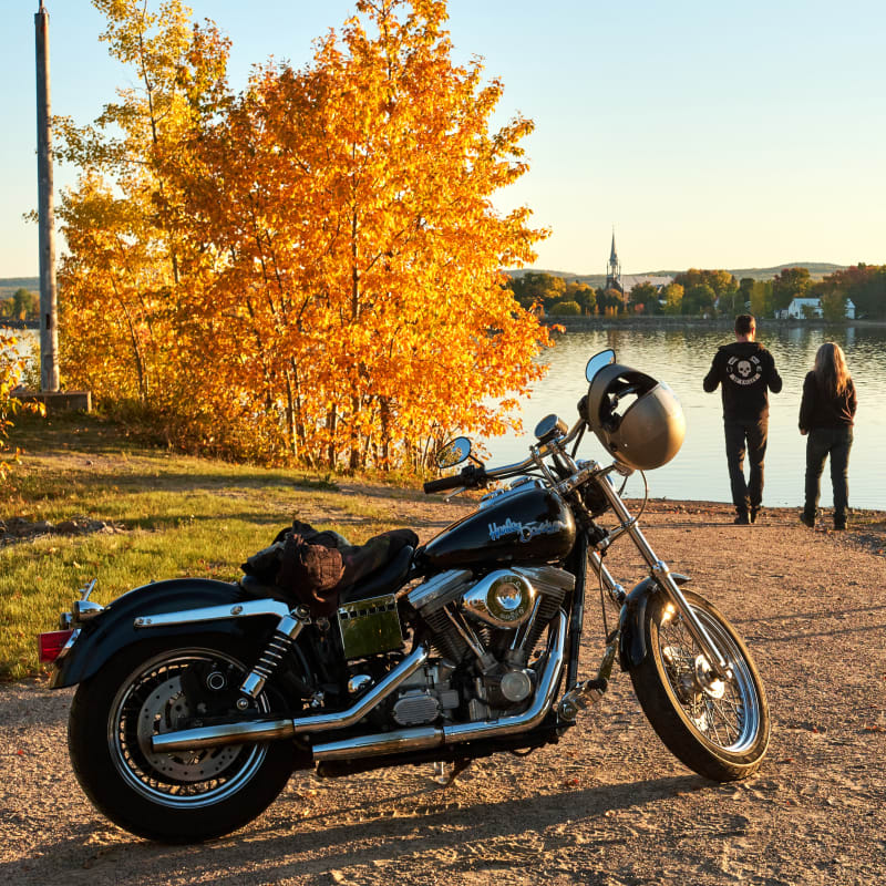 Destination Lac-Saint-Jean a couple of bikers taking a break by the water in the fall
