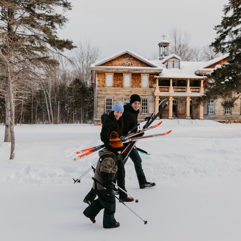 Destination Lac-Saint-Jean a family strolling with their skis in the winter