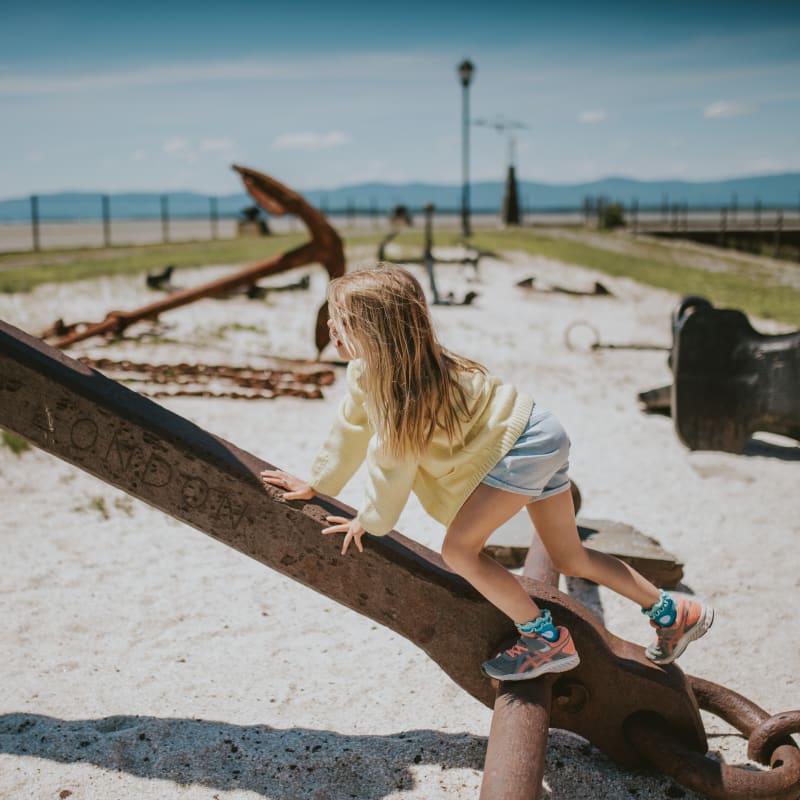 Girl playing on old anchors.