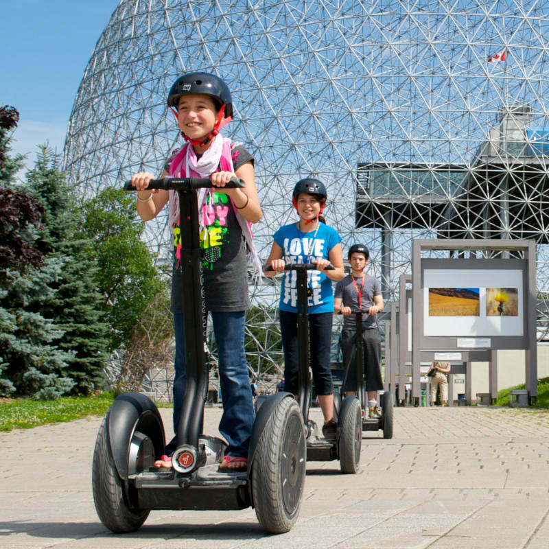 Jeune fille et ses parents en Segway devant la Biosphère