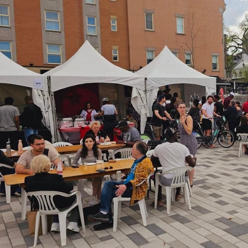 AfriCa Fest - Numerous people sitting at tables, near food trucks and kiosks.