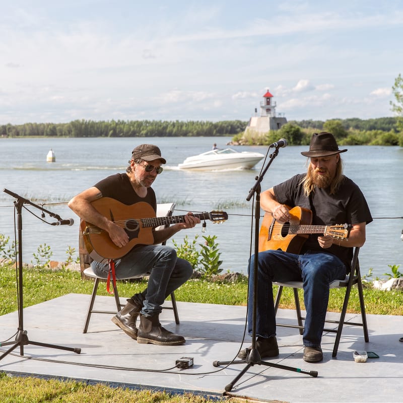 Deux guitaristes qui jouent au bord de l'eau.
