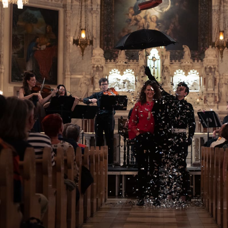Montreal Baroque Festival - Concert inside a church. A man holds an open umbrella with falling confetti.