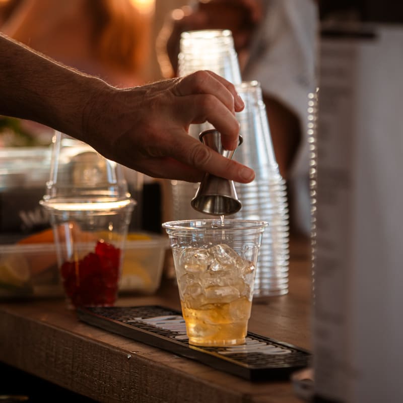 Festival Parasol - A hand pours liquid into a cup filled with ice