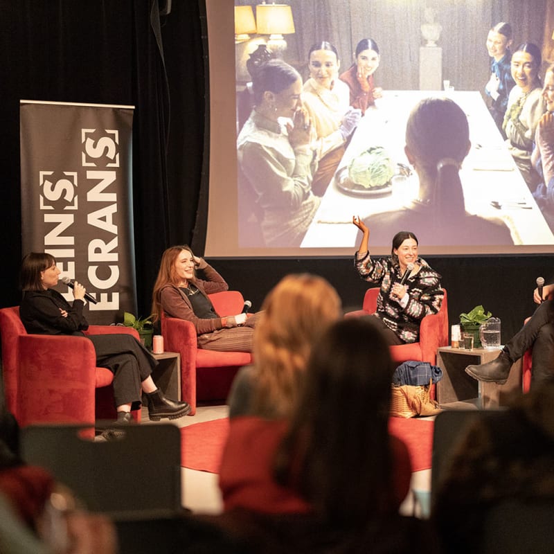 Festival Plein(s) Écran(s) - Un panel de personnes discute sur une scène, avec une projection derrière eux 