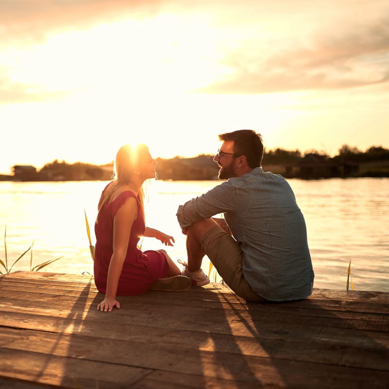 Couple assis sur un quai au coucher de soleil 