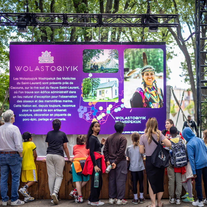 Group of adults and kids in front of an explanatory panel.