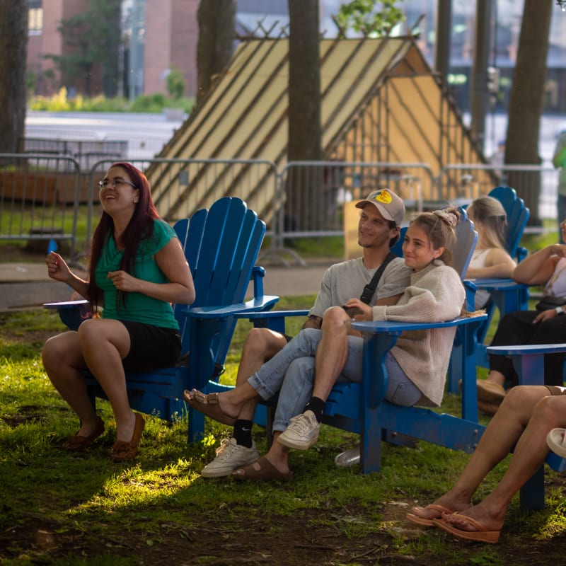 People sitting on outdoor chairs in front of a show.